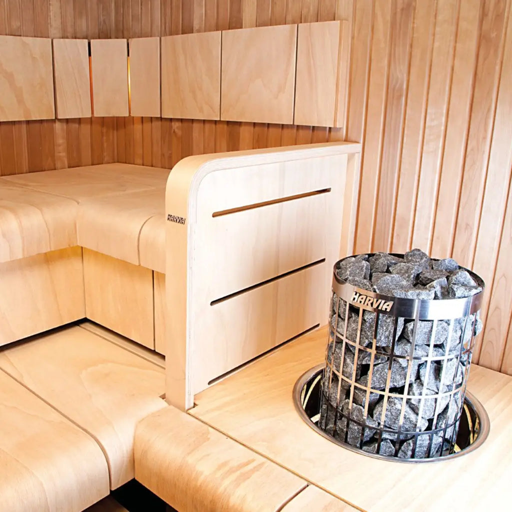 Wooden sauna interior with a Harvia heater containing hot stones by Finnish Sauna Builders