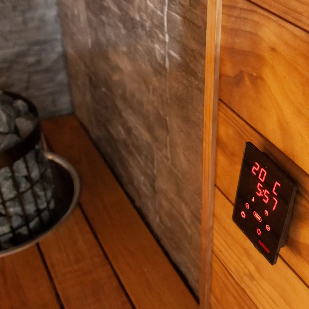 Digital thermometer on a wooden sauna wall with stone background by Finnish Sauna Builders