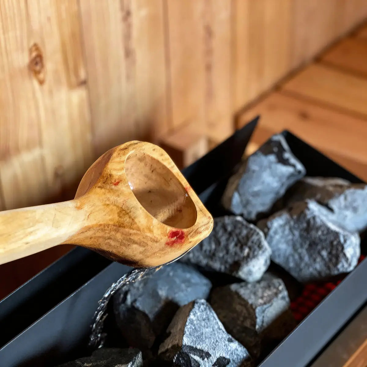 Homecraft H-Series Electric Sauna Heater Wooden spoon over hot stones in a sauna setting
