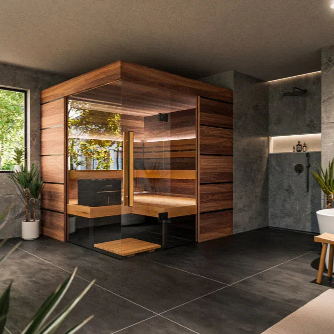 Wooden sauna cabin in a modern bathroom setting with gray tiles and plants.